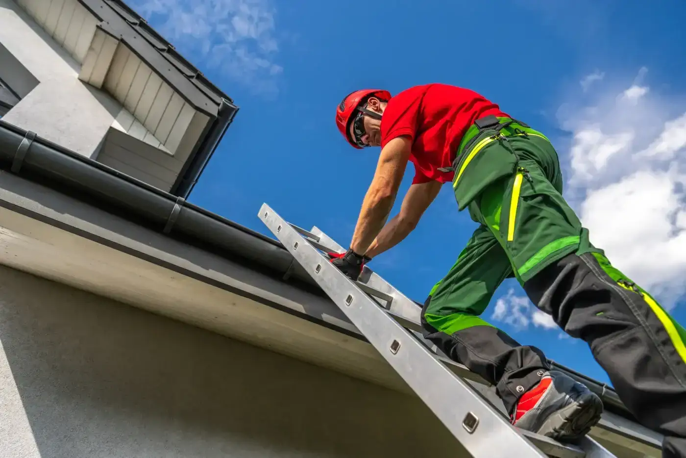 A technician in protective gear climbs an extension ladder toward the roofline to inspect storm damage and perform a roof repair.
